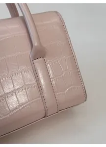 Dettaglio della borsa rosa in pelle a coccodrillo che mostra trama e cuciture nere