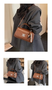 Détail d'un sac baguette marron vintage avec boucle en X et breloque en perles de bois