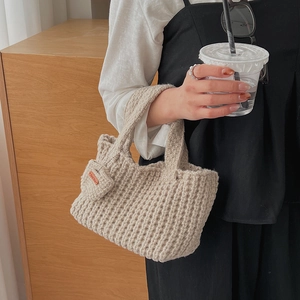 Détail du sac à main beige tricoté main avec texture laine et étiquette Hand Made en cuir