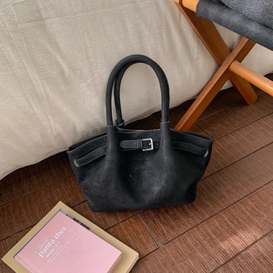 Detail shot of black suede bucket bag with silver buckle and elegant pleated texture