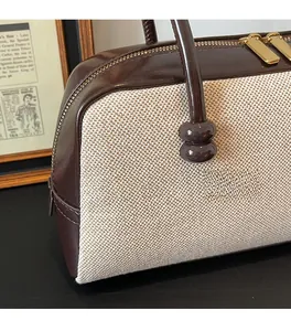 Detail of dark brown patent leather and beige woven fabric on a vintage Boston bag