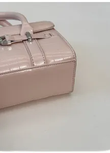 Dettaglio della base ampia di una borsa rosa in pelle con motivo a coccodrillo
