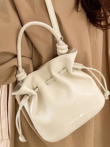 Fashionable cream leather drawstring bucket bag with knotted shoulder strap for women