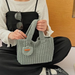 Détail du sac tricoté main vert sauge avec texture gaufre et breloque en cœur