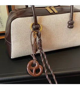 Detail of canvas and leather patchwork handbag featuring golden zippers and creative charms