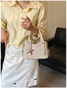 Close-up of minimalist cream white handbag with silver starfish charm and metal feet
