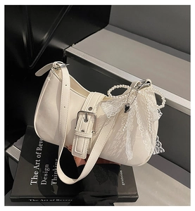Détail du sac hobo avec boucle argentée, bordure en dentelle et pendentif perle