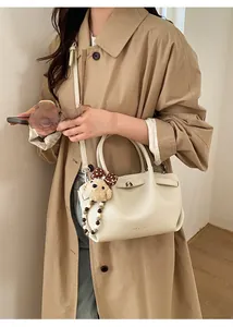 Close-up of cream textured leather bucket bag with a cute plush bear charm detail