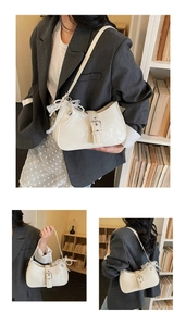 Détail du sac sous le bras minimaliste avec nœud en dentelle et pendentif perle cœur