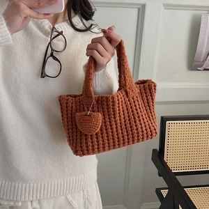 Gros plan d'un sac à main orange fait main avec motif tricoté et pendentif en forme de cœur