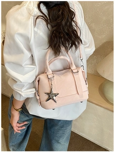 Detail of light pink Boston bag with silver star charm and smooth leather texture