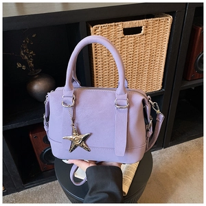 Close-up of lilac Boston bag with round handles and shiny gold star pendant detail
