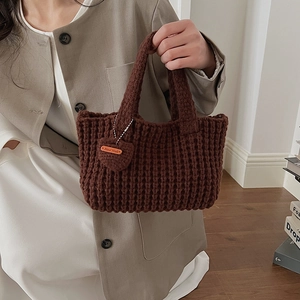 Gros plan détaillé d'un sac à main en maille marron avec breloque en forme de cœur