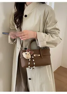 Brown lychee leather tote bag with gold lock and cute bear charm shown on a model