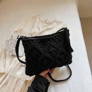 Macro shot of black handmade woven cotton shoulder bag featuring boho tassel details