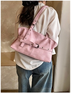 Detail view of pink faux leather tote bag with silver metal buckles on a shoulder strap