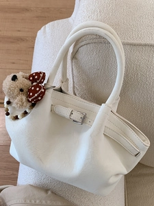 Chic beige pleated bucket bag with decorative metal buckle and plush puppy charm