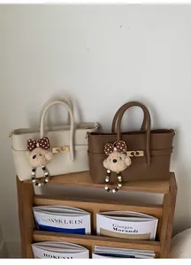 Detail of lychee pattern leather handbags with metal locks and teddy bear charms