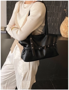 Detail view of black faux leather tote bag with silver metal eyelet strap on model