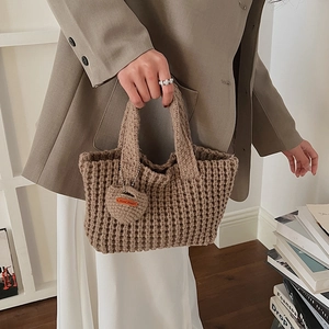 Gros plan du sac cabas fait main en maille gaufrée marron avec un pendentif en cœur