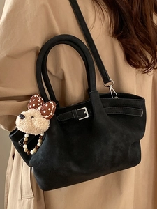 Chic black suede bucket bag with adjustable strap and cute plush puppy charm accessory