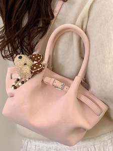 Pink pleated bucket bag with teddy bear charm shown as a stylish crossbody handbag