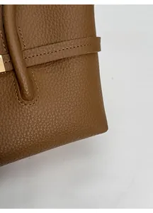 Close-up of brown lychee grain leather texture and precise stitching on the handbag