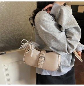Détail du sac beige avec boucle décorative et accessoire de nœud en dentelle perlée