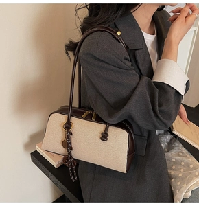 Detail of canvas shoulder bag showing dual gold zippers and vintage leather trim details