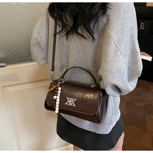 Détail du sac bandoulière vintage marron foncé avec pompon ethnique et boucle en métal