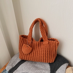 Détail d'un sac cabas en tricot orange fait main avec breloque ronde et étiquette en cuir