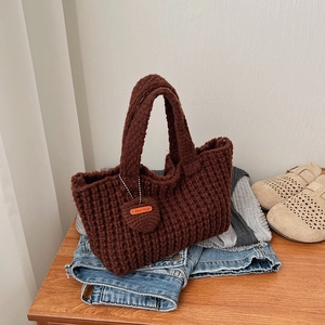 Détail du sac cabas au crochet marron foncé avec pendentif cœur et étiquette en cuir