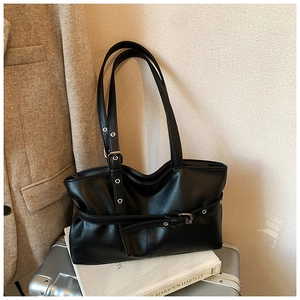 Detail of black leather tote bag with adjustable metallic buckle strap on studio setting
