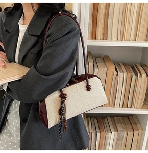 Detail of canvas and burgundy leather stitching on large capacity baguette shoulder bag