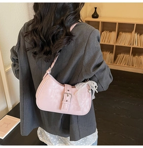 Détail du sac hobo rose avec bord en dentelle et breloque cœur en perles sur veste grise