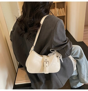 Vue détaillée du sac croissant crème avec boucle en métal et ruban perle sur un blazer gris