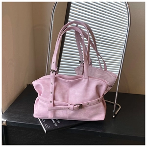 Detail of a pink matte tote bag featuring a decorative buckle belt and metal eyelets