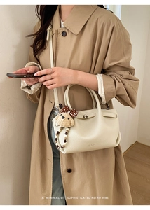 Detail of off-white lychee texture leather bucket bag with cute bear charm accessory