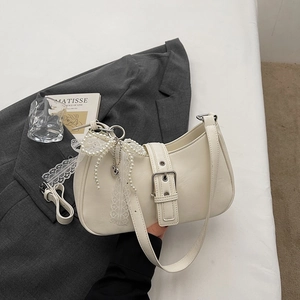 Détail du sac hobo avec nœud en dentelle, chaîne de perles et pendentif cœur argent