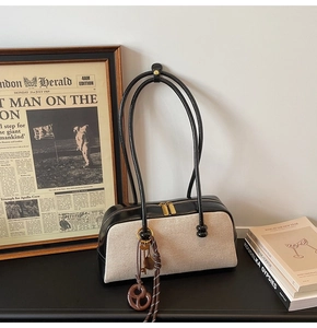 Detail of canvas shoulder bag with long shoulder strap and retro decorative pendant