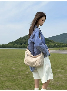Detailed view of beige large capacity messenger bag with adjustable strap and front pocket