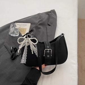 Détail du sac sous le bras noir en nylon avec boucle argentée et nœud en dentelle perlée