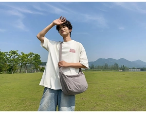 Outdoor shot of a grey minimalist canvas crossbody bag styled with casual outfit