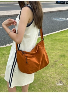 Close-up of orange nylon crossbody bag featuring front zipper pocket and adjustable strap