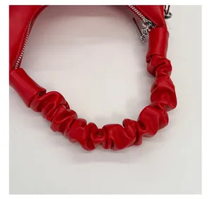 Detail of red pleat handle handbag featuring silver metal zipper and soft PU leather