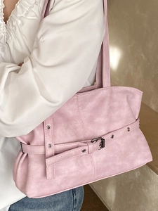 Pink faux leather tote bag with decorative metal eyelet belts on a female model