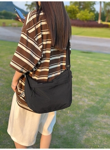 Detail of black waterproof nylon crossbody bag with adjustable wide strap and zip pocket
