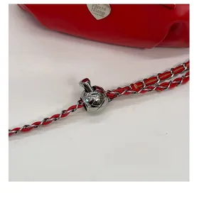 Detail of red leather chain strap with adjustable silver ball buckle on bucket bag
