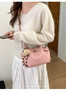 Pink bucket bag detail with litchi texture, cute bear pendant, and beaded handle strap