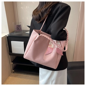 Detail of pink tote bag with embossed textures and decorative silk scarf on shoulder